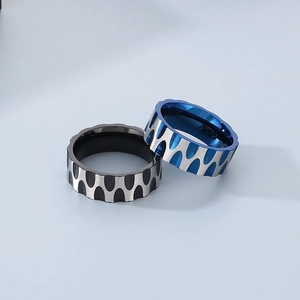 Macro detail of wave texture stainless steel rings with blue and black brushed finishes