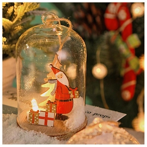Close-up of glass Christmas cloche with wood Santa, LED light, and snowy base