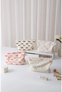 Detailed close-up of colorful bow-patterned cotton makeup bags with brand labels