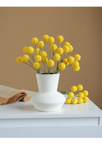 Artificial yellow billy balls in a white ceramic vase for minimalist home decor