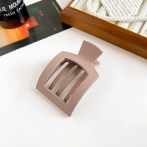 Detail shot of a matte dusty pink rectangular hair claw clip on a white table surface