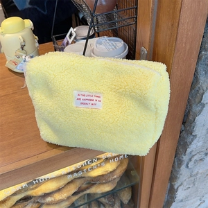 Detail of yellow fuzzy fleece makeup bag with a zipper and inspirational text patch