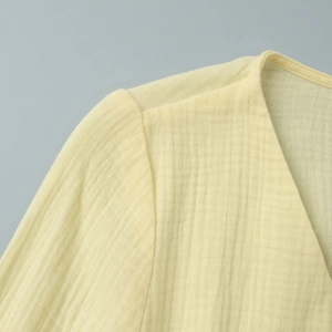 Detail of V-neckline and textured cotton crepe fabric on a pale yellow summer dress