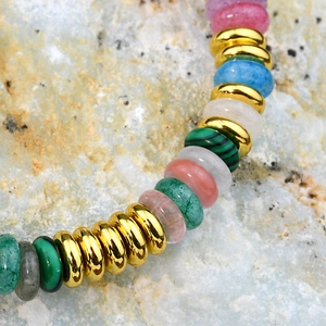 Macro shot of colorful natural semi-precious stone disc beads and golden metal spacers