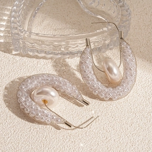 Detail view of U-shaped silver earrings with metal mesh and embedded white pearl decoration