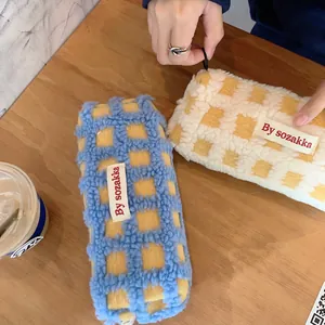 Macro view of checkered fleece pencil cases on a wooden desk with a cozy vibe