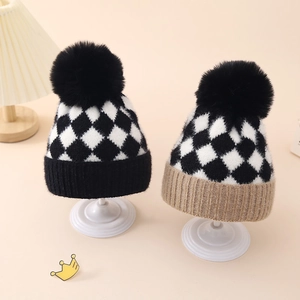 Detail of checkered knit baby beanies with fluffy pom poms and soft ribbed cuffs