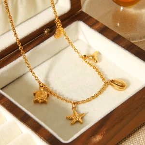 Detailed shot of golden sea charms including turtle and starfish on a wooden jewelry box