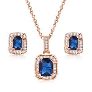 Macro detail of rose gold jewelry set featuring square blue stones and micro-pave crystals