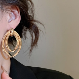 Gros plan de boucles d'oreilles ovales à triple couche en finition dorée polie
