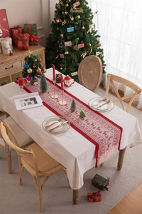 Close-up of red Christmas table runner with white reindeer patterns and decorative tassels