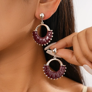 Detail of dark burgundy leather geometric hoop earrings with silver bead accents on model