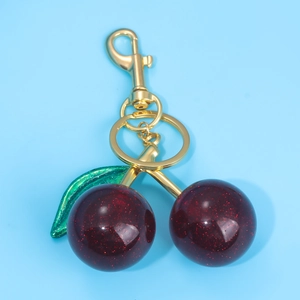 Detail of dark red glitter cherry keychain with green leaf and gold metal lobster clasp