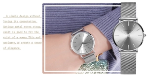 Close-up of minimalist silver mesh strap watch with sunray dial on female wrist