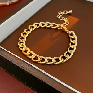 Detail of gold curb chain bracelet with extender on a luxury dark brown leather tray