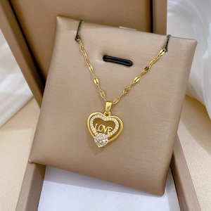 Detail der goldenen Herzkette mit Mikro-Zirkonia und LOVE-Gravur auf Schmuckständer