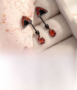 Detail of cat ear stud with red zircon inlay and drop pendant in titanium steel