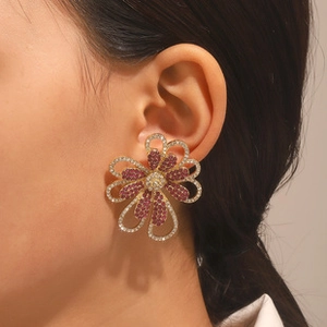 Gros plan de boucles d'oreilles fleurs baroques dorées avec cristaux rose et strass