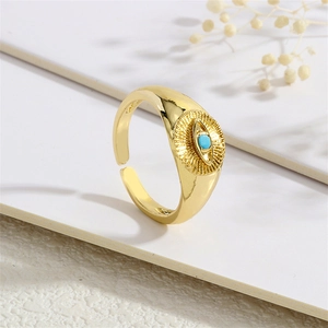 Close-up of gold plated evil eye ring with blue zircon inlay on white textured background