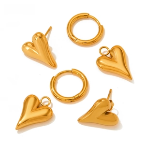 Flat lay of gold stainless steel heart earrings and round hoops on white background