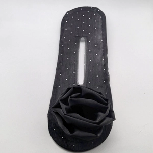 Detail view of black mesh hair bun maker with floral accent and silver studs on white background