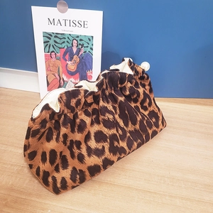 Leopard print velvet clutch bag with large pearl clasp on light wood surface