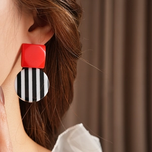 Close-up of retro black and white striped resin earrings worn by a model