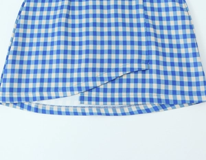 Detail of blue and white plaid skirt showing asymmetric hemline and sewing craftsmanship