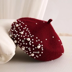 Detail of burgundy wool beret featuring elegant white pearls and sparkling rhinestones
