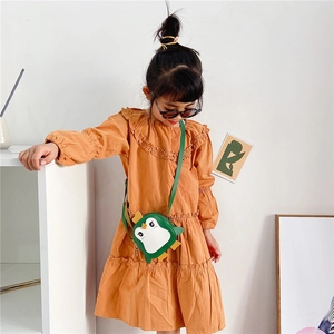 Detailed view of cute penguin shaped crossbody bag paired with mustard yellow cotton dress