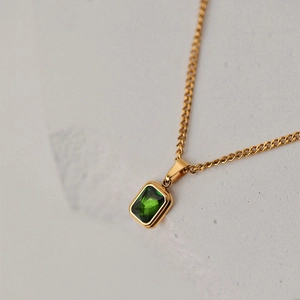 Macro shot of rectangular emerald gemstone pendant with a polished gold-plated chain