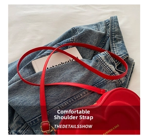 Detail of red heart-shaped crossbody bag with adjustable strap and fashion lettering