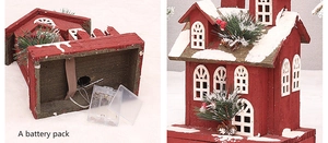 Detail of red wooden Christmas house showing bottom battery compartment and festive pine decor