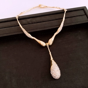 Détail d'un collier pendentif goutte d'eau plaqué or orné de nombreux cristaux blancs pavés