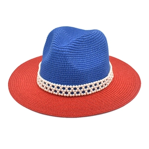 Detail of red and blue contrast straw hat featuring a luxury pearl mesh decorative band