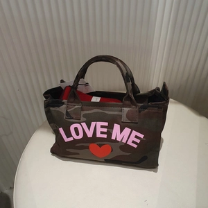 Detail view of camouflage canvas tote bag with pink Love Me text and red heart graphic