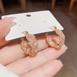 Detail of gold hoop earring featuring a pink cat eye stone and pave crystal accents