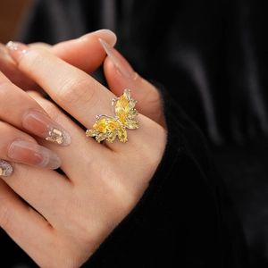 Gros plan d'une bague papillon en zircon jaune étincelant sur la main d'un mannequin