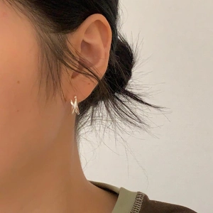 Close-up of minimalist silver cross hoop earrings worn by a model for a stylish look