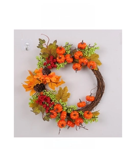 Detail of harvest wreath with orange pumpkins, red berries, pine cones and autumn leaves