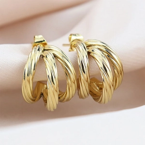 Detailed macro view of triple-layered golden twisted hoop earrings with a spiral texture