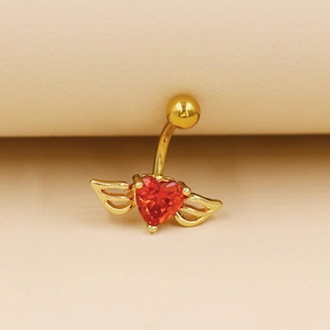 Détail du piercing de nombril doré avec cœur rouge en gemme et ailes dorées