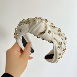 Detailed view of white satin knotted headband with gold-set rhinestones for women