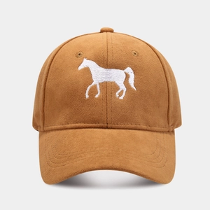 Detail of horse embroidery on a caramel brown suede baseball cap with a curved brim