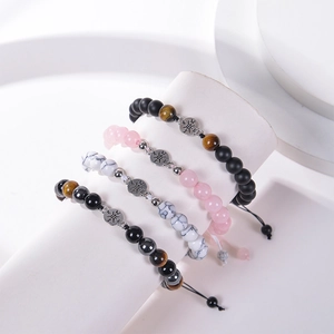 Detail view of four beaded bracelets with compass charms in tiger eye and natural stone