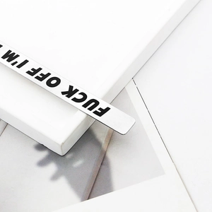 Polished stainless steel bookmark with engraved text FUCK OFF I'M READING on a desk