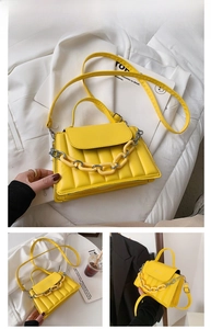 Detailed view of yellow quilted crossbody bag featuring fashion text and chunky chain strap