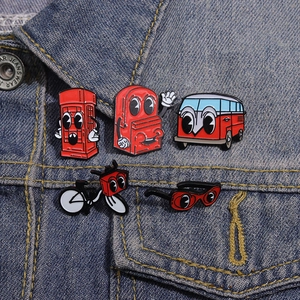 Five vintage red enamel pins including bus and phone booth on a denim jacket pocket