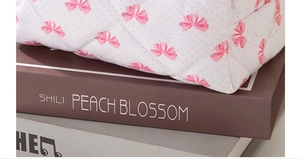 Détail d'une trousse à maquillage matelassée avec nœuds roses et pois sur tissu blanc