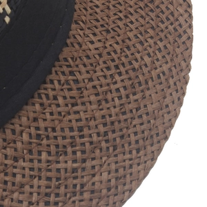 Dettaglio cappello di paglia marrone con trama intrecciata e nastro nero elegante